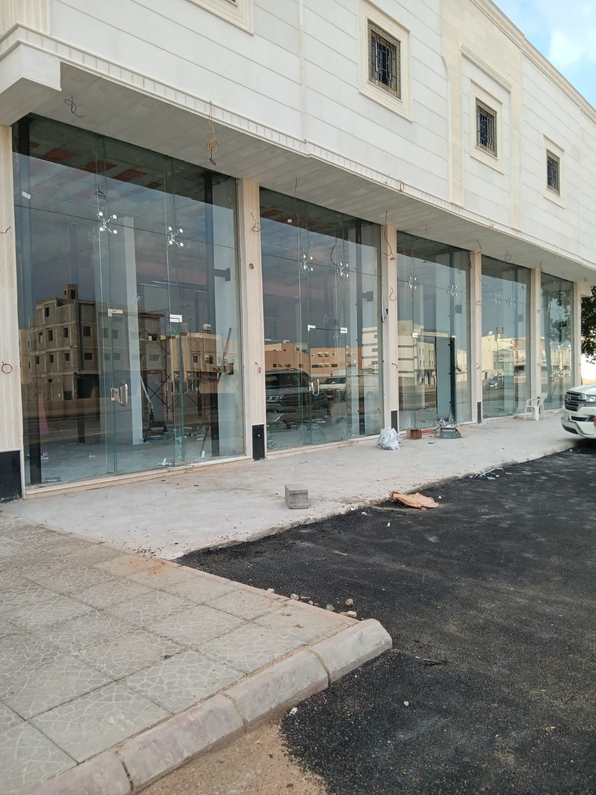 واجهة محل تجاري من الخارج مركّب عليها ألواح زجاج سيكوريت شفافة كبيرة بإطارات داكنة، مع رصيف وشارع أمامها في وضح النهار.